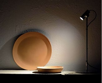 Foco de iluminación puntual destacando elementos decorativos sobre pared de textura natural