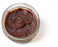 Top down view of a little, clear, open container of brown pumpkin butter