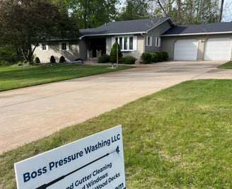 Boss Pressure Washing LLC yard sign in front of a freshly cleaned driveway and home.
