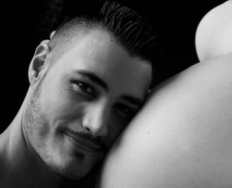 photo de grossesse avec le portrait du futur papa posant sa tête sur le ventre fond noir