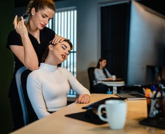 a busy professional getting a massage at her desk by a Remedly physio
