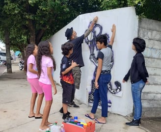 Jovem aplicando stencil – Estudante pratica a aplicação de stencil em uma parede da escola.