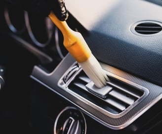 a person cleaning a car's dashboard with a brush