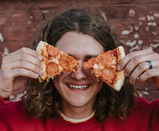 Un adolescent avec des parts de pizza devant ses yeux