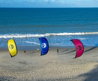 3 kites voando em frente a praia.
