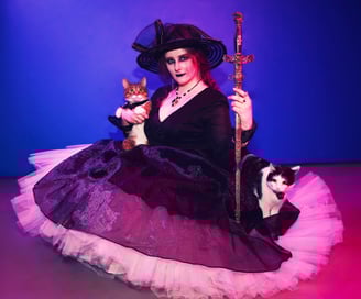 a woman in a witch costume holding a cat and a sword