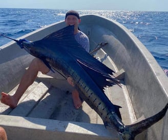 Fisherman with an impressive sailfish caught during a deep-sea fishing charter in Zanzibar