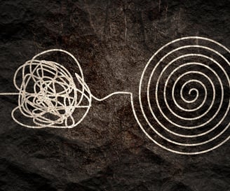 black and white image.  piece of string, tangled on one side, perfectly coiled on the other