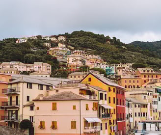 Hillside view of colorful houses in Bogliasco - with lush greenery - Italian flag in the foreground