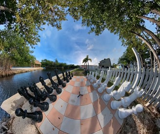 a chess game with chess pieces on a checkered floor next to the waterfront