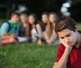 a boy sitting on the grass with his head in his hands