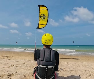 adolescente controlando o kitesurf de frente para a o mar.