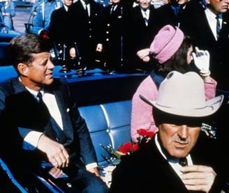 a man in a suit and hat sitting in a car
