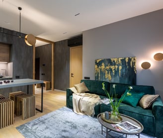 an open plan space with a emerald green sofa and coffee table and a kitchen island