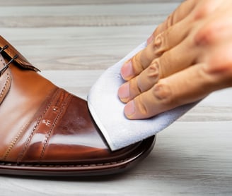 a person cleaning a shoe with a shine wipe