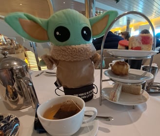 Little Green stuffed Animal on table with Tea cup and cakes