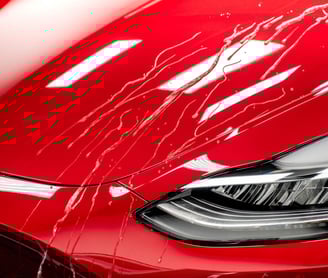 a red tesla detailing car with a shiny ceramic coating hood and a shiny cleaned clear headlights