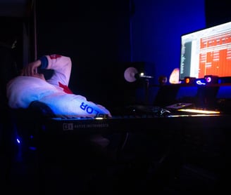 a man is slumped over in a chair in the dark. With a computer screen on.