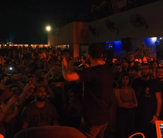 a man standing in front of a crowd of people performing rap music in lebanon