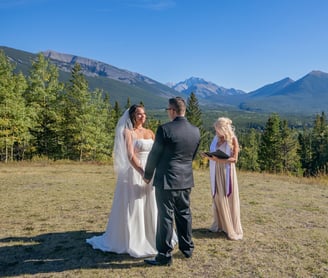 a bride and groom having a wedding ceremony in front of a mountain at Kananaskis village