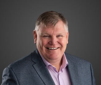 a man in a grey suit and pink shirt