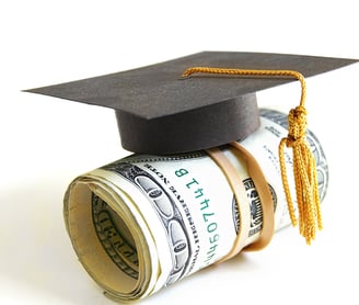 a graduation cap on top of a roll of money