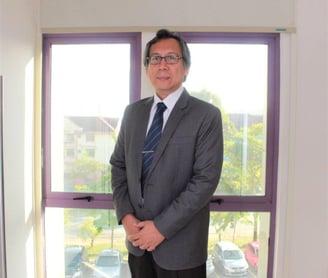 A man in suit standing in front of glass windows