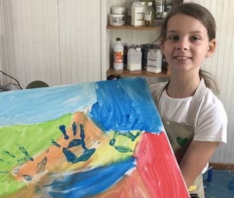 Photo de Magali STrassel, art-thérapeute, montrant une petite fille fière de montrer sa peinture