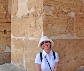 author d. ann hall in a hat and sunglasses standing in front of an Egyptian column