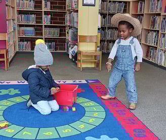 two children interacting in a library, playing on kids carpet