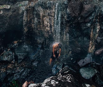 Man washing under waterfall