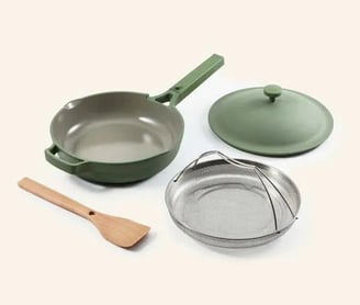 a set of three pots and pans with a wooden spoon