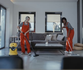 two people in red overalls cleaning a living room