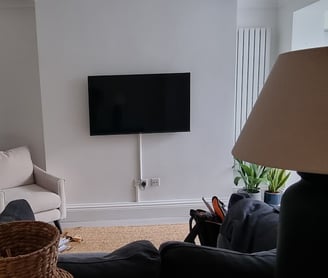 TV mounted on a wall in a living room with surface trunking. Camden
