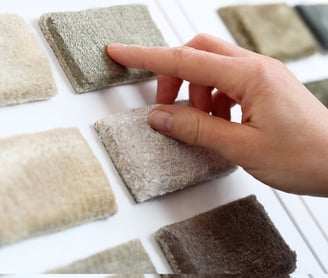 a person's hand holding a piece of carpet with a finger on it