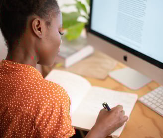 a woman sitting at a desk with a notebook and pen