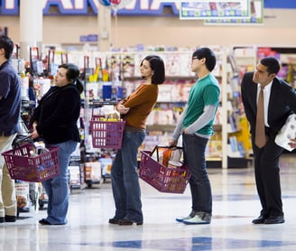 um grupo de pessoas em pé na fila de um supermercado