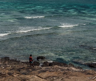 a person standing on a rock in the ocean