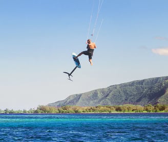 Kaituodamas su kite foil sportininkas išoką į orą virš vandens.
