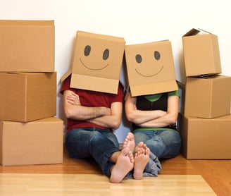 a man and woman sitting on the floor with boxes of boxes with smiley faces