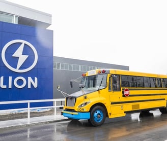 a yellow school bus parked in front of a lion