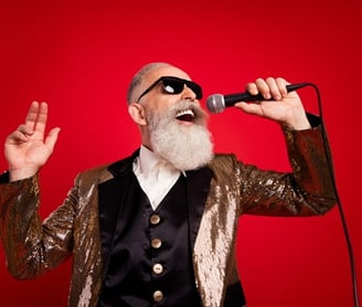 a older man with a beard and sunglasses on a red background