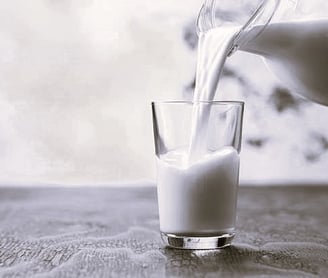 a pitcher of milk being poured into a glass