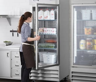 a woman in a apron and aprons is standing in front of a refrigerator