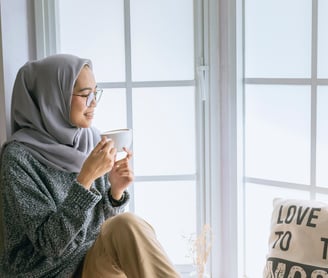 A beautiful girl with Good daily habits for better mental health enjoying her coffee by the window