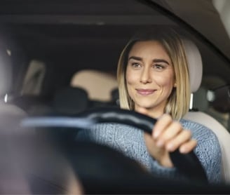 a woman driving a car with a steering wheel