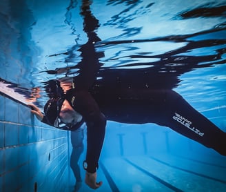 a man in a wetsuit is swimming in a pool