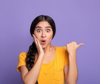a woman with a surprised look on her face and holding her hands up to her