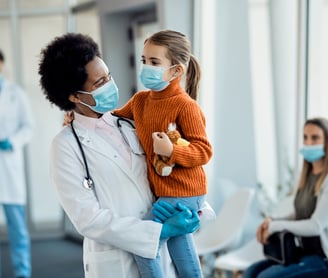 Médica sorrindo com uma menina no colo