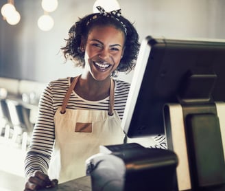 A happy store owner standing behind her point of sale system.